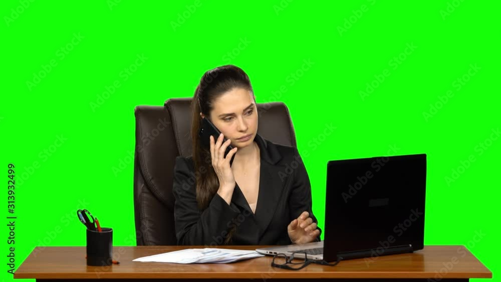 Girl working on a laptop then answers the call by mobile phone. Green screen Girl working on a laptop then answers the call by mobile phone. Green screen