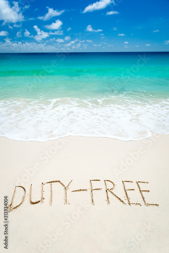 Duty Free travel shopping message written in smooth sand on bright tropical beach