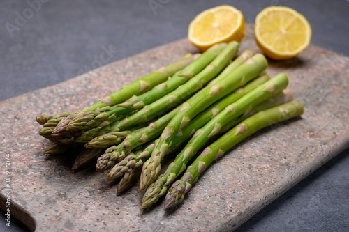 Bunch of fresh green raw organic asparagus with lemon ready to cook