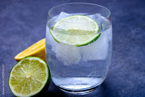 Cold drinking mineral water served in glass with ice cubes and green lime