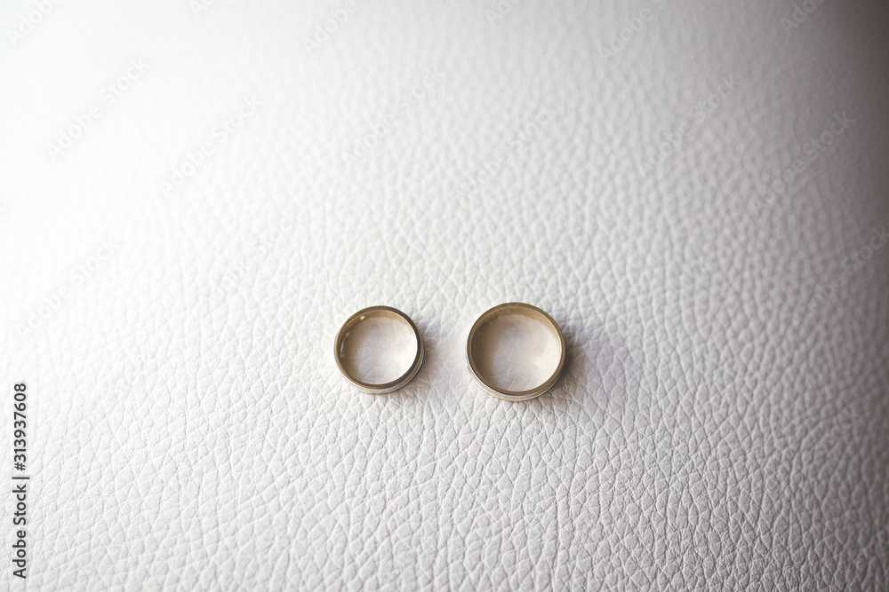 a pair of golden wedding rings on white leather background a pair of golden wedding rings on white leather background