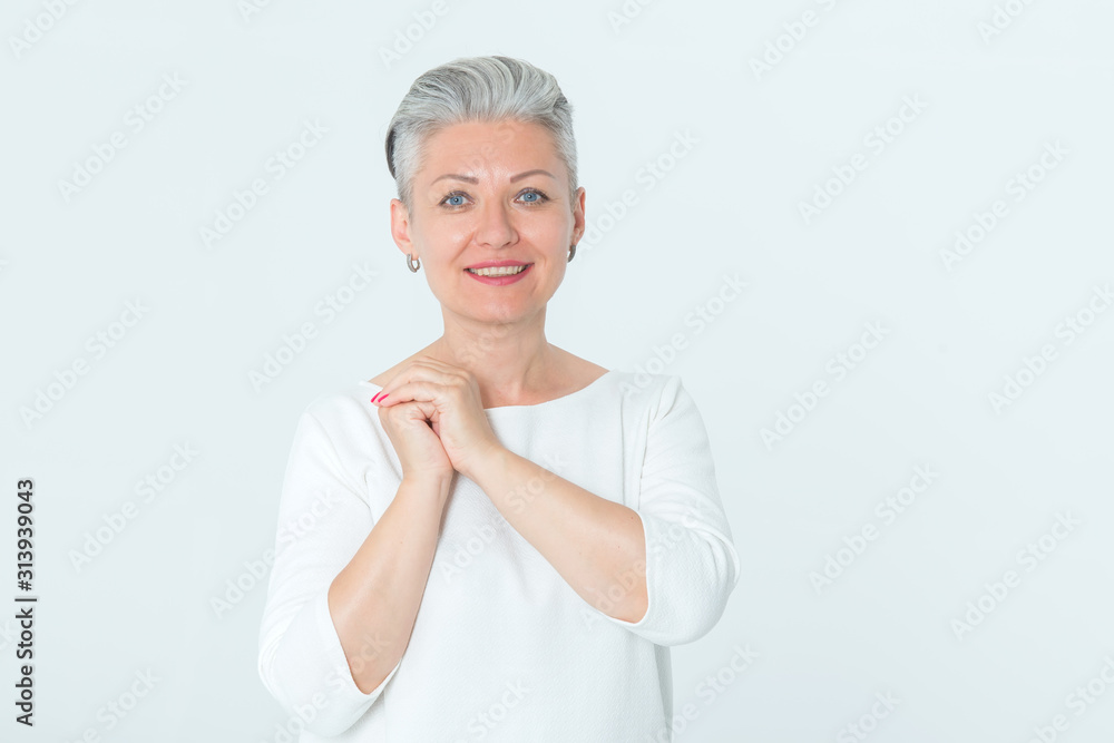 Portrait of a happy mature woman standing on a light background..Female middle age. Portrait of a happy mature woman standing on a light background..Female middle age.