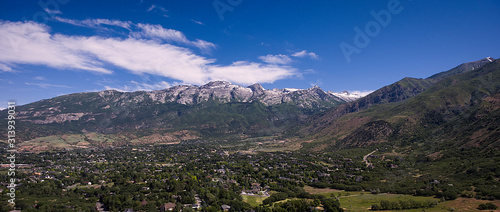 An aerial drone shot captures Lone Peak Mountain and Alpine Utah on a sunny summer day. 