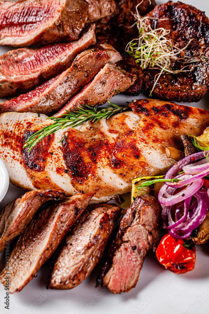 Turkish cuisine. Assorted different meat on the grill, lamb, chicken, pork with grilled vegetables. Serving dishes in a restaurant on a white plate. background image, copy space