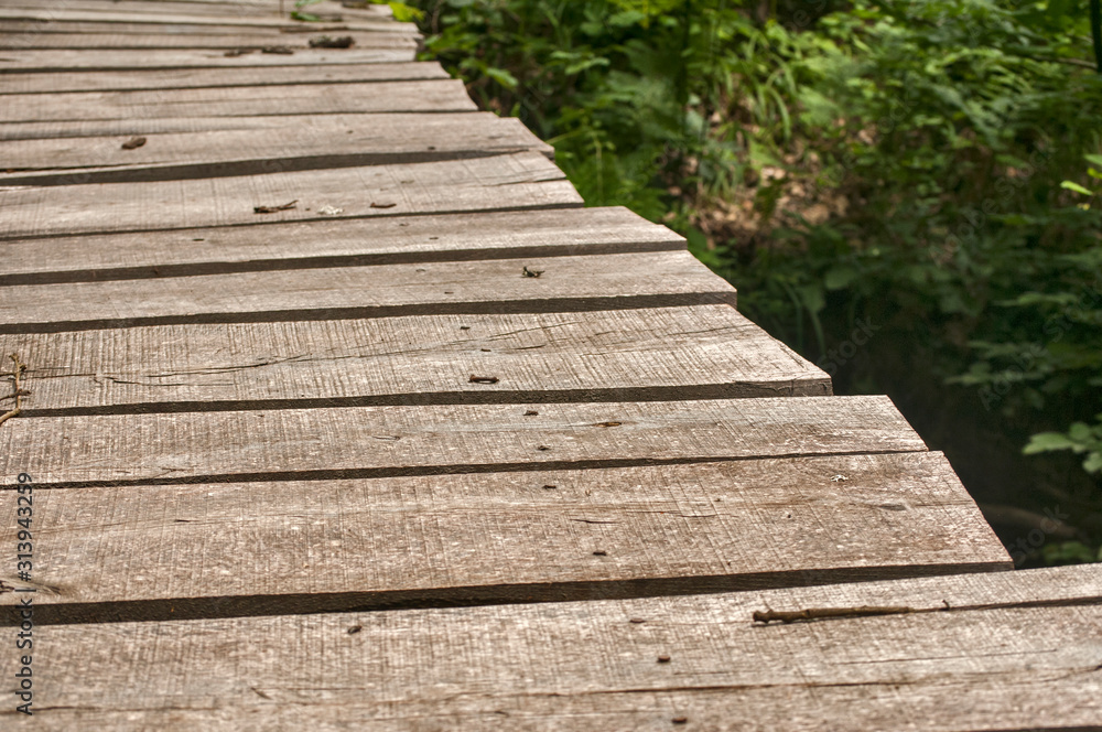 Small weathered wooden boards bridge over river waters closeup Small weathered wooden boards bridge over river waters closeup