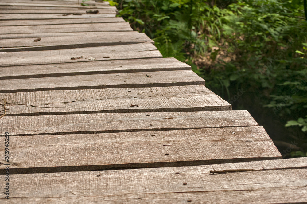 Small weathered wooden boards bridge over river waters closeup