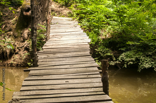 Small weathered wooden boards bridge over river waters closeup