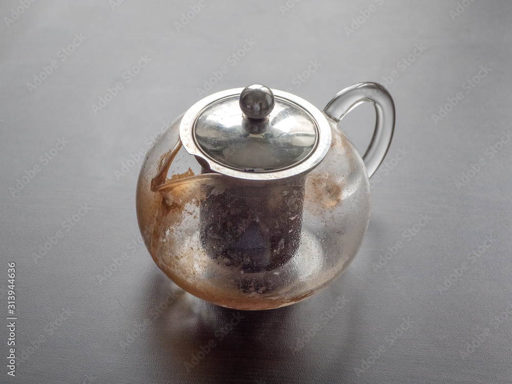 Dirty glass teapot. Tea scale on the teapot. Cleaning the teapot at