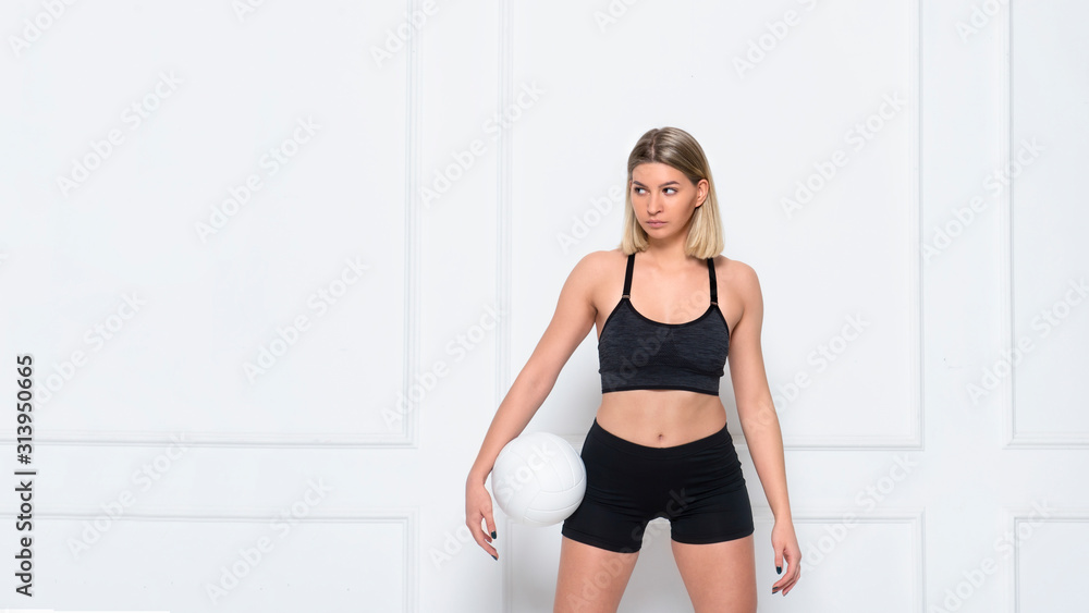 Young woman volleyball player on white wall background