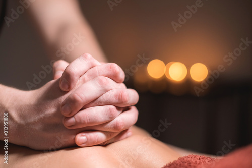 Close-up of the hands of a male masseur doing back massage to a girl at the spa. Low key high contrast shallow depth of field © yanik88