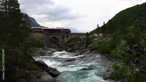 Slow motion. Rauma railway train cross bridge. Raumabanen sightseeing in Norway. Scenic train ride from Dombas to Andalsnes. Famous Norwegian landmark. Slow motion.  photo