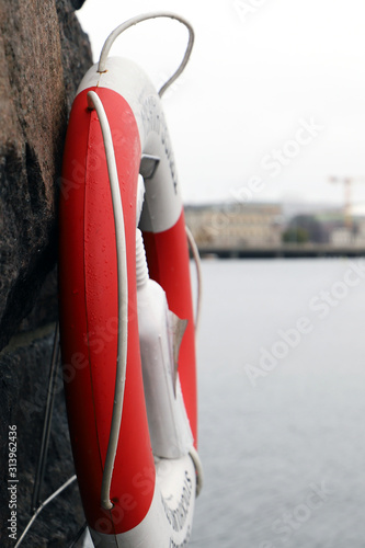 Lifebuoy hanging on a citywall next to a river on a rainy day photo
