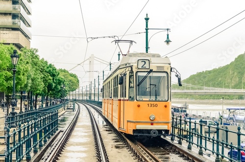 number 2 orange tram passes along rails along the Danube River from Erzhebet Bridge near Belgrade Embankment. Budapest, Hungary.