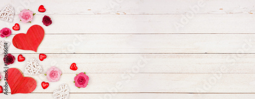 Valentines Day banner with corner border of hearts, flowers and decor against a rustic white wood background. Copy space.