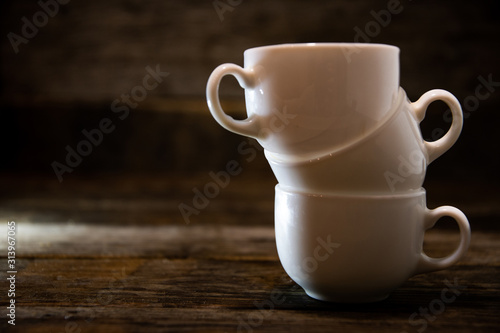 Three white espresso cups stacked on top of each other  on a wooden table.