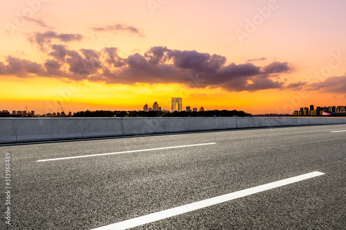 Empty asphalt highway and Suzhou city skyline with colorful sky at sunset.