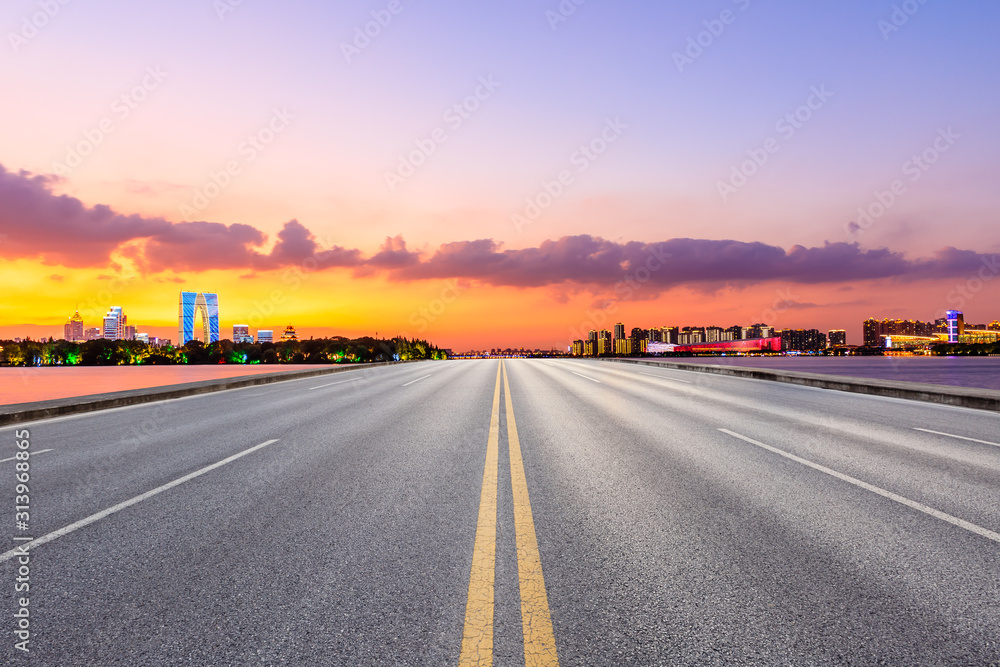 Empty asphalt highway and Suzhou city skyline with colorful sky at sunset.