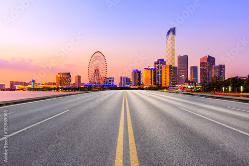 Empty asphalt highway and Suzhou city skyline with beautiful colorful sky at sunset.