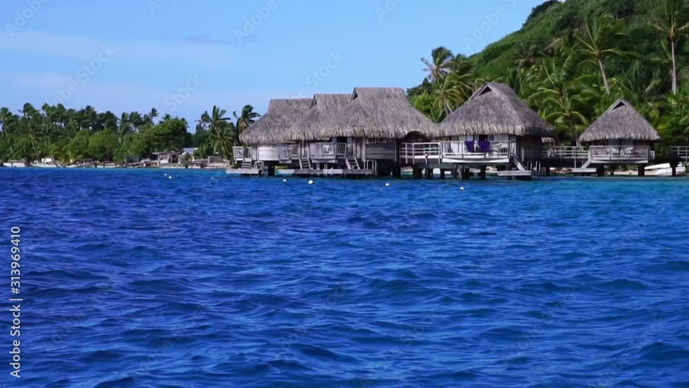 Low angle aerial glide view of overwater bungalow villas in turquoise lagoon. Bora Bora, Tahiti French Polynesia. Luxury honeymoon vacation, romantic getaway, exotic resort destination. Low angle aerial glide view of overwater bungalow villas in turquoise lagoon. Bora Bora, Tahiti French Polynesia. Luxury honeymoon vacation, romantic getaway, exotic resort destination.