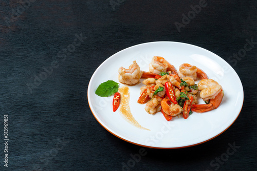 Stir fried shrimp with basil on a white plate ,On a black wooden floor
