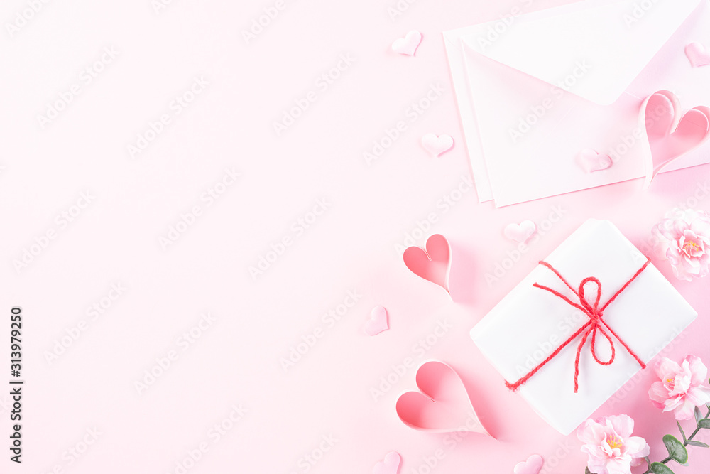 Pink paper hearts with cover letter and gift box on Light pink pastel paper background. Love and Valentine's day concept.