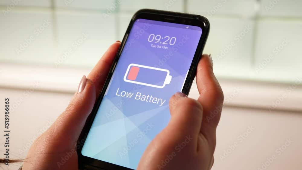 Woman holding a phone with a low battery icon warning. Woman holding a phone with a low battery icon warning.