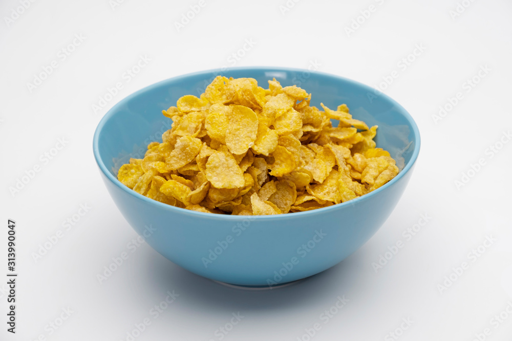 Golden cornflakes in the blue bowl isolated on white background Golden cornflakes in the blue bowl isolated on white background