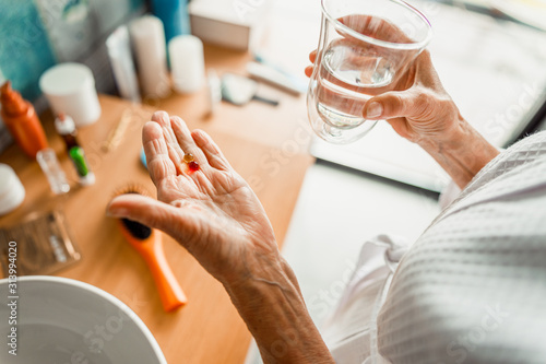 Elderly woman holding pills and glass of water