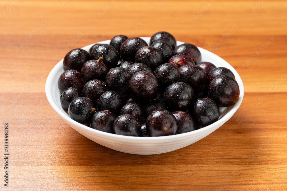 Detail of fruit in bowl with water droplets. Jaboticaba or Jabuticaba is the native Brazilian grape tree. Species Plinia Cauliflora. Brazilian Berry. Detail of fruit in bowl with water droplets. Jaboticaba or Jabuticaba is the native Brazilian grape tree. Species Plinia Cauliflora. Brazilian Berry.