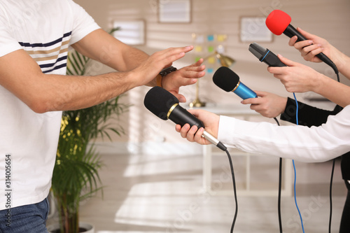 Man avoiding journalist's questions at interview indoors, closeup view