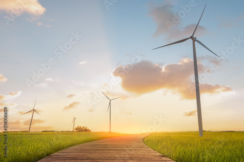 Green energy concept. Wind turbines and wooden bridges with green field and sunset backgrounds. © Thanumporn