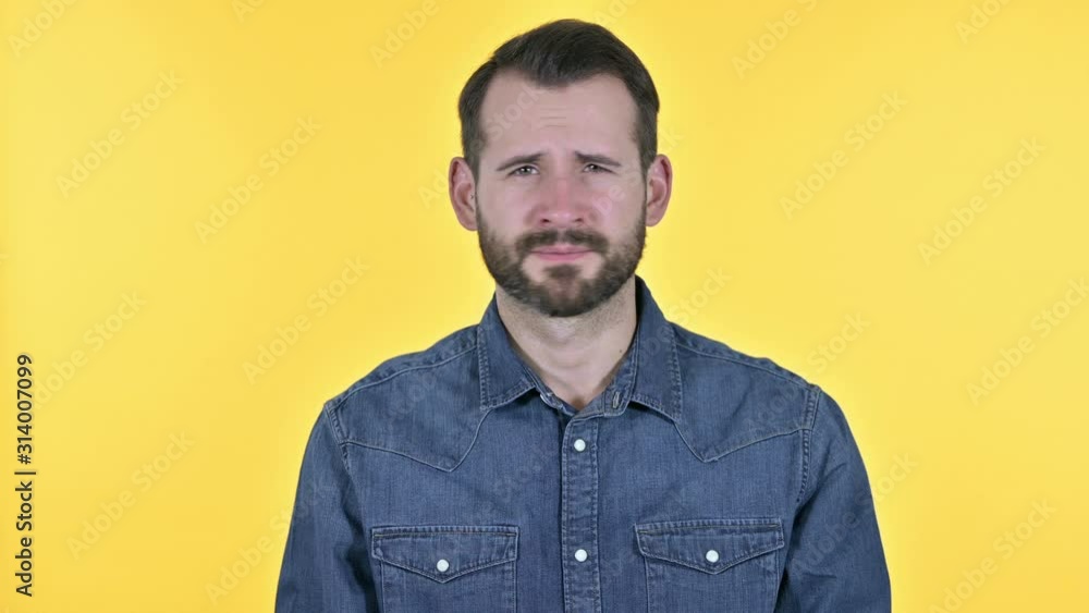 Disappointed Beard Young Man Reacting to Failure, Yellow Background Disappointed Beard Young Man Reacting to Failure, Yellow Background