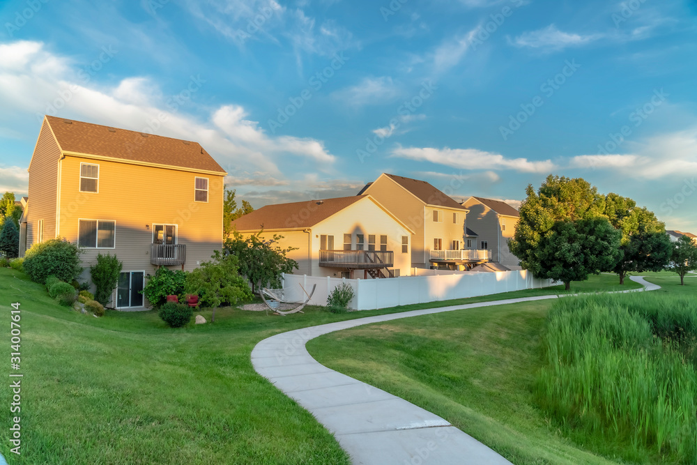 Pathway on lush green grassy ground in front of houses with balconies and stairs Pathway on lush green grassy ground in front of houses with balconies and stairs