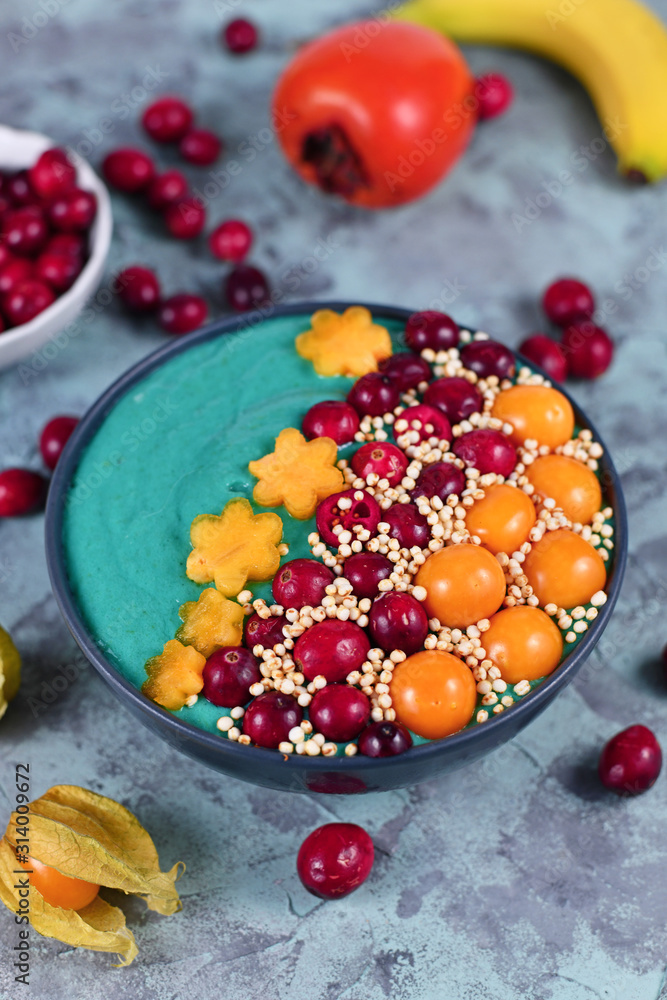 Healthy yogurt and fruit smoothie bowl with natural green spirulina powder  and decorated with cranberries, physalis and kaki fruits and puffed quinoa  grains Stock Photo | Adobe Stock