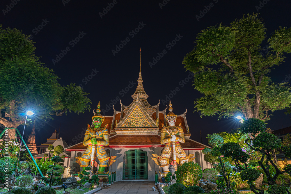 Large illuminated temple Wat Arun after sunset seen accross river Chao Phraya Bangkok, Thailand.golden Buddha in side temple Wat Arun the biggest and tallest pagoda in the world