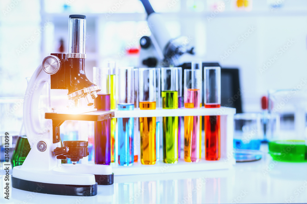 Microscope and Colorful test tubes with lab glassware in laboratory background, research and Scientific concept