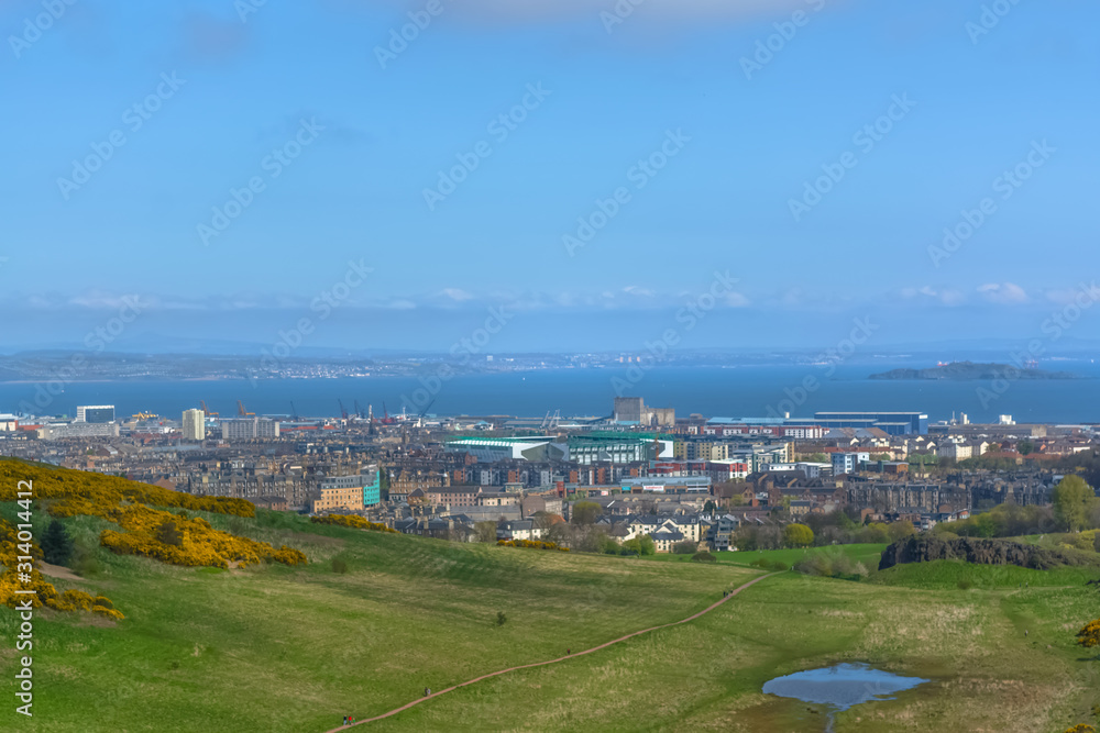 General aerial view from the Holyrood Park to the Edinburgh downtown city, buildings and sea on background General aerial view from the Holyrood Park to the Edinburgh downtown city, buildings and sea on background