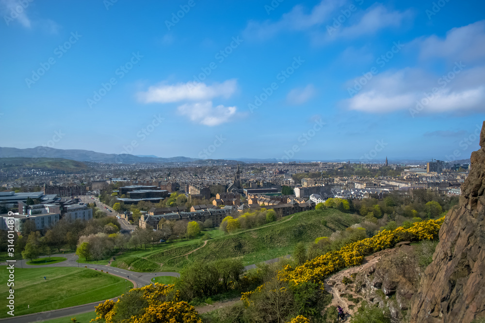 General aerial view from the Holyrood Park to the Edinburgh downtown city, monument buildings, mountains and parks on background