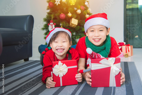 Little asian girl and her brother lying on the floor with gift box and smiling together at home in Christmas holiday. © gamelover