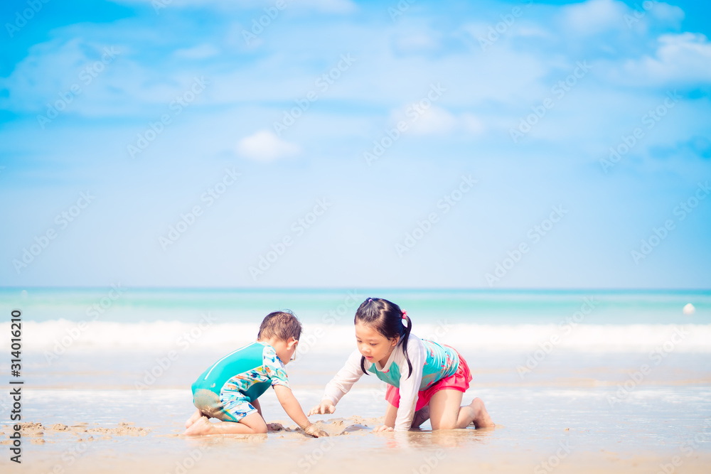 5.10 years old Little asian girl playing on the beach with her 2.9 year old baby brother.Family with children at the beach. EF, Motor skills development.Sibling on Vacation summer and relax concept.
