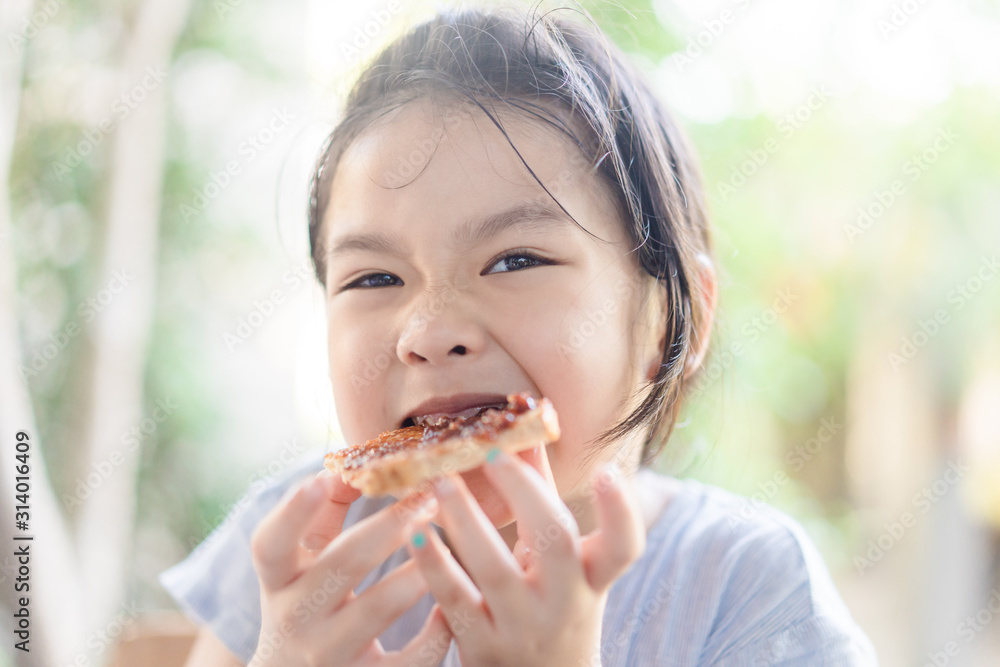 Funny little asian girl eating tasty toasts with strawberry jam spread for breakfast. Hungry face and Delicious face in kid girl. Funny little asian girl eating tasty toasts with strawberry jam spread for breakfast. Hungry face and Delicious face in kid girl.