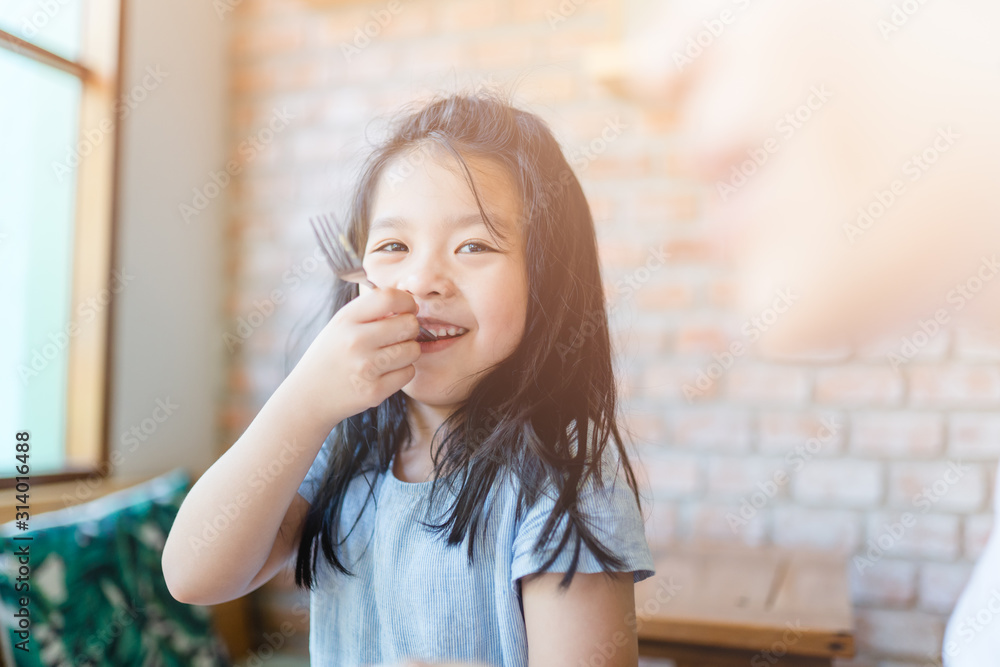 Smiley happy little asian girl eating bakery and she have fork in her mouth.Hungry and Delicious face she ready for eat everything in restaurant. Smiley happy little asian girl eating bakery and she have fork in her mouth.Hungry and Delicious face she ready for eat everything in restaurant.