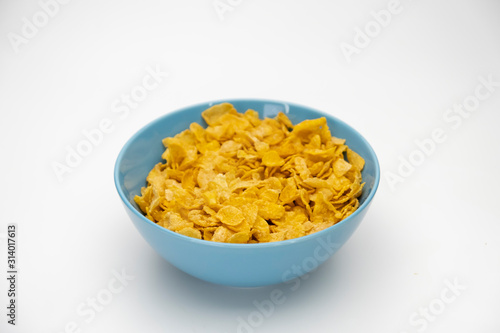 Golden cornflakes in the blue bowl isolated on white background