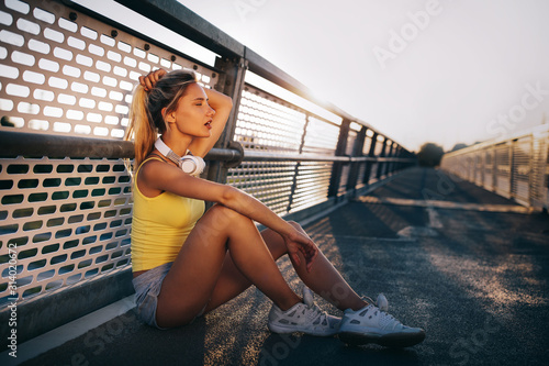 Portrait of fit cheerful blonde woman resting after a run in a city