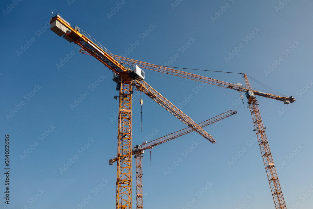 Luffing jib tower crane at large scale construction site over blue sky Luffing jib tower crane at large scale construction site over blue sky