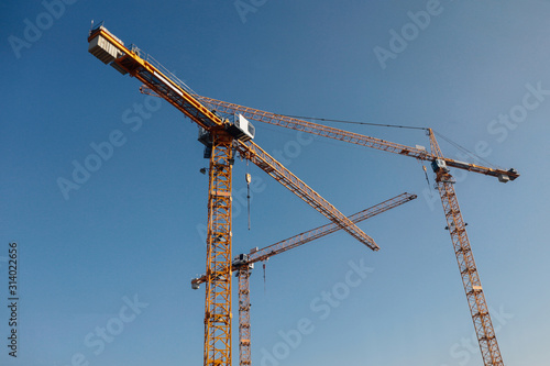 Luffing jib tower crane at large scale construction site over blue sky