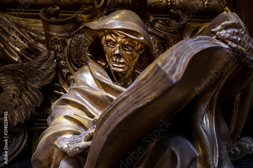 Close up of bronze stature portraying Death holding the book the of dead