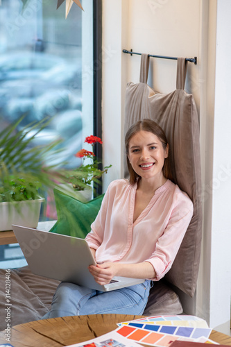 Smiling young designer working with her laptop photo