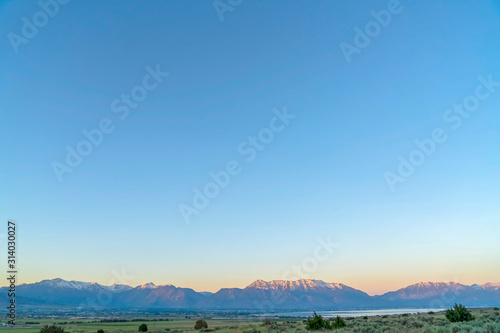 Panoramic view of mountain with snowy peak against sky with an orange glow