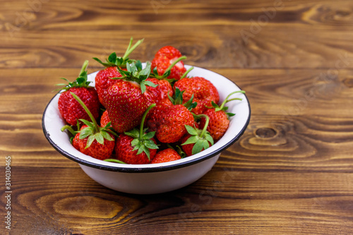 Fresh ripe strawberry in white bowl on a wooden table